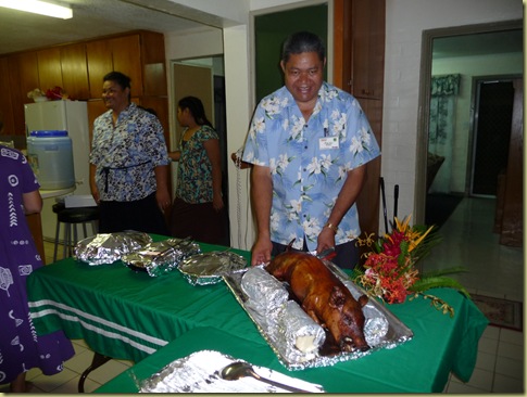 Kioa displays the glazed/roasted pig as part of the feast for Area Principal's Conference.  Moane Kupu in the background is Inoke Kupu's wife.
