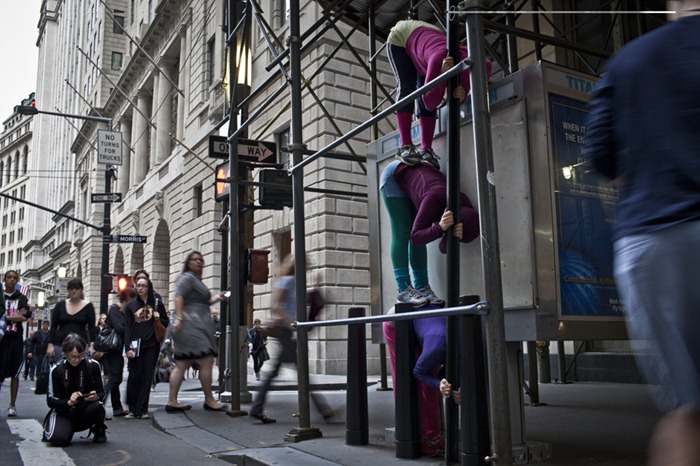 Audience members watch as performers situate themselves into position during a piece entitled "Bodies in Urban Spaces" by choreographer Willi Dorner.  Starting at sunrise, the performers inched their way into different spaces throughout lower Manhattan.CREDIT: Bryan Derballa for The Wall Street JournalNYBODIES