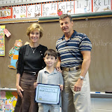 Kai with his 2nd grade teacher and the school principal, holding his certificate for the Young Authors' Project