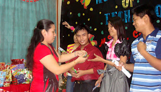 Ma'am Beth distributes prizes to parlor games winners.