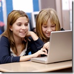 Two young girls working on a laptop in the classroom