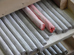 2 still soft red rods, which will become coral red after vulcanization. Heat and sulfur attacks the organic pigments - in the end, the bright colors seen here exit drastically changed. Its a magic science to know in advance, which color in the beginning produces which color in the end. On top of it - changes in extrusion tecnique, changes in climate outside - winter or summer - will always slightly vary results.