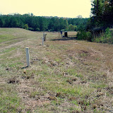 A well-vegetated site showing monitoring wells and landfill gas extraction system. The PVC pipes mark the location of a trench and provide access for any required maintenance in the future.