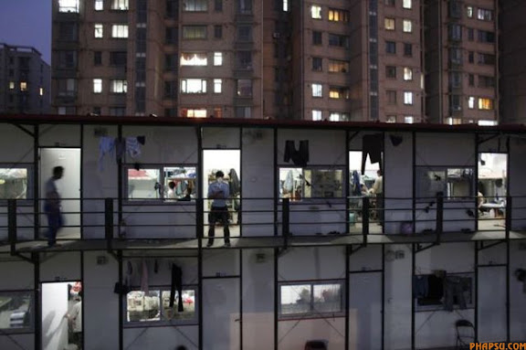 RNPS IMAGES OF THE YEAR 2009 - A migrant construction worker checks his mobile phone outside his dormitory after a working shift at the Shanghai World Expo 2010 construction site in Shanghai April 15, 2009.China's annual GDP growth slipped to a record low in the first quarter, but the quarter-on-quarter increase might point to a recovery, a domestic news portal reported on Wednesday.  REUTERS/ Nir Elias (CHINA BUSINESS POLITICS)