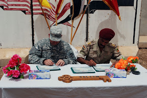 Capt. Rich Turvey, Btry. A, 2nd Bn., 20th FA Regt. commander, signs over JSS Salaam to 1st Lt. Jassim Abbas, 3rd Co., 1st Bn., 32nd IA Bde. commander, at the transfer ceremony near Numaniyah June 20. In accordance with the security agreement between the United States and Iraq, Iraqi Security Forces now have full ownership of security in their cities, villages and localities. U.S. Army photo by Sgt. 1st Class Joe Thompson)