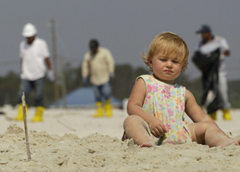 Workers in protective suits walk towards 14-month-old Hannah Cooney as they comb the beach at Dauphin Island, Ala. The community was bracing for a possible land fall of an oil spill. CHARLIE RIEDEL / AP
