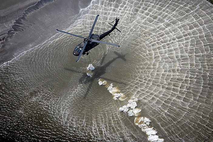National Guard helicopters drop sand bags in a breach in the beach just west of Grand Isle, La., in an effort to protect the delicate marsh lands from the approaching oil slick moving westward from the Deepwater Horizon spill, 10 May 2010. Ted Jackson / AP