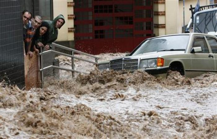 People look on as a street with vehicles is engulfed by heavy flooding in downtown Funchal, Madeira February 20, 2010. Credit: REUTERS / Duarte Sa