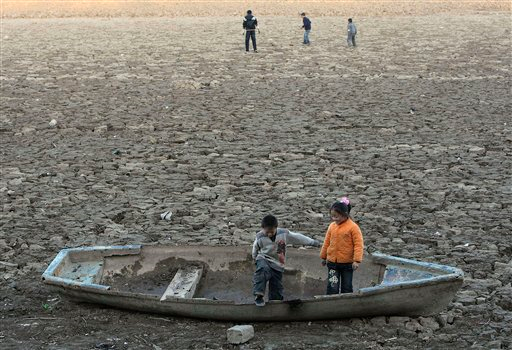 Two children play on a boat at the dried-up riverbed in a park in Zhengzhou of China's Henan province, Monday, Feb. 9, 2009. Delivery of water to ease a severe drought that hit grain-growing areas in northern China has been successful, a vice minister of water resources said Tuesday, with rain also forecast for the parched region, after Beijing has declared an emergency across China's north, where 3.46 million people still lack adequate drinking water and winter wheat crops are withering in the fields. AP