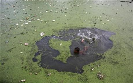 A boy swims in the polluted waters of the Buriganga river in Dhaka May 14, 2009. The water of the Buriganga river has turned pitch black due to the dumping of millions of tonnes of human and industrial waste according to local media. Credit: Reuters / Andrew Birajbr /