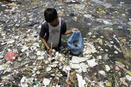 A boy collects plastic materials near a polluted coastline to sell in Manila April 9, 2008. Credit: Reuters / Cheryl Ravelo