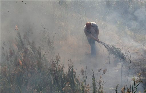 A local resident, one of the volunteers enlisted to help firefighters, battles a grassfire near the village of Velino, some 140 km (87 miles) east of Moscow, Saturday, Aug. 14, 2010. Russia has been battling the fires for nearly three weeks. The fires have destroyed provincial towns and villages, and together with the drought have cost Russia a third of its wheat crop. AP Photo / Ivan Sekretarev