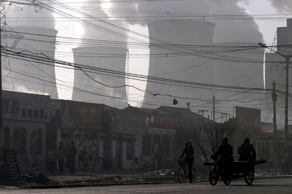 Huozhou, China: Morning commuters pass under the cooling towers of the Shengtou Power Plant , Shanxi Province. The Shengtou plant is one of the country's largest coal burning power plants. Photograph: Qilai Shen / EPA via The Guardian.
