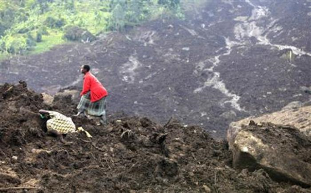 A woman searches for her missing relatives on a pile of soil in Bududa village, 210 km (130 miles) east-northeast of the Ugandan capital Kampala, March 3, 2010. The landslide in eastern Uganda has killed at least 80 people and villagers are digging with bare hands and simple tools in the hope of finding survivors, a government minister and Ugandan media said on Tuesday. REUTERS / James Akena