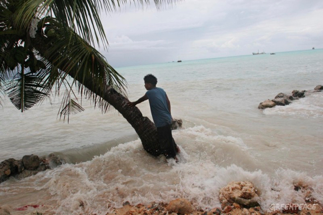 Pita Meanke, of Betio village, stands beside a tree as he watches the 'king tides' crash through the sea wall into his family's property, on the South Pacific island of Kiribati, 10 February 2005. &copy; Greenpeace / Jeremy Sutton-Hibbert