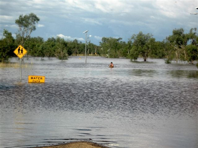 A man wades through a flooded Fitzroy Crossing road in Western Australia, 12 March 2011. Ken McLeod