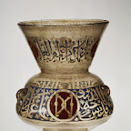 This lamp is the earliest datable example of its kind known to have hung in an interior that still survives. The inscription states that it was made for the tomb of the Mamluk emir Aydakin al-cAla'i al-Bunduqdar (died 1285) in Cairo. The emblem of the Keeper of the Bow, a pair of confronted bows against a red background, appears nine times on this lamp. A rare mistake by the calligrapher is evident on the neck, where the word bunduqdar (Keeper of the Bow) has been misspelled as a meaningless word, bunqud-dar.