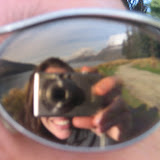 Katie takes a picture of the mountain reflection in Dan's sunglasses.