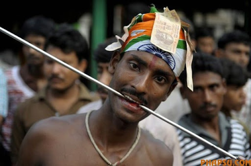 An Indian Hindu devotee adjusts a metal rod pierced through his tongue during the ritual of Shiva Gajan at a village in Bainan, some 80 kms south of Kolkata, on April 14, 2010. Devotees believe that by enduring the pain, Shiva, the Hindu god of destruction, will grant their prayers. Thousands took part in the month-long festival which culminates with the worship of Shiva on the auspicious day of Chaitra Sankranti, the last day of the Bengali calendar year. AFP PHOTO/Deshakalyan CHOWDHURY (Photo credit should read DESHAKALYAN CHOWDHURY/AFP/Getty Images)