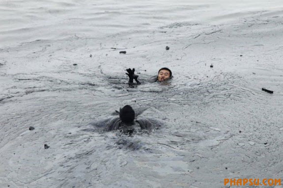 A worker attempts to rescue his co-worker from drowning in the oil slick while attempting to fix an underwater pump during the oil spill clean-up operations at Dalian's Port in Liaoning province July 20, 2010. A pipe transporting crude oil from a ship to a storage tank blew up on Friday evening, causing a second pipeline nearby to  explode also, according to Xinhua News Agency. No one was injured. The port has since resumed normal container operations. REUTERS/Jiang He/Greenpeace (CHINA - Tags: ENERGY ENVIRONMENT IMAGES OF THE DAY DISASTER) NO SALES. NO ARCHIVES. FOR EDITORIAL USE ONLY. NOT FOR SALE FOR MARKETING OR ADVERTISING CAMPAIGNS. MANDATORY CREDIT