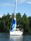Man standing on spreader putting spinnaker in sock.