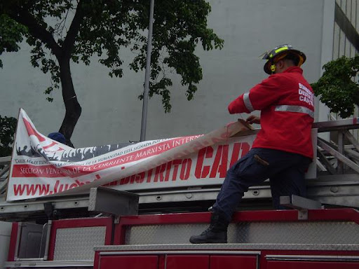 Bombero del Distritto Capital pone la pancarta de Lucha de Clases encima de una camioneta bombero 