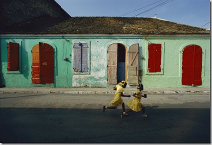 Two girls run from the photographer as he tries to take their picture.  The pho tographer noted that almost all of the inhabitants of Cap Haitien behaved this way whenever he tried to photograph them.