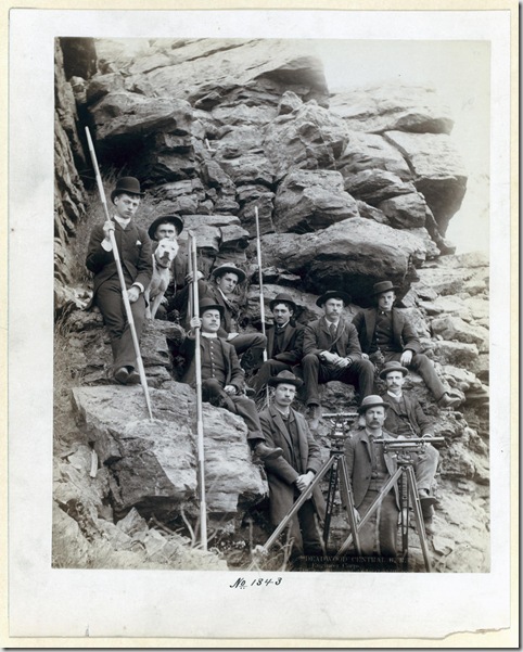Title: Deadwood Central R.R. Engineer Corps
Outdoor group portrait of ten railroad engineers and a dog, posing with surveyors' transits on tripods and measuring rods, on the side of a mountain. Most of the men are sitting; all are wearing suits and hats. [1888]
Repository: Library of Congress Prints and Photographs Division Washington, D.C. 20540