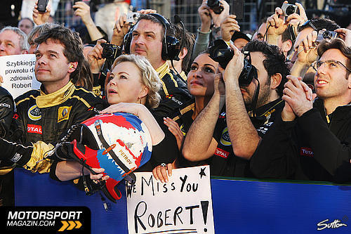 Оксана Косаченко вместе с механиками Lotus Renault у подиуме Гран-при Австралии 2011 с надписью We Miss You Robert