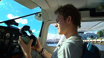 Нико Росберг примеряет наушники пилота перед полетом на самолете над Мельбурном