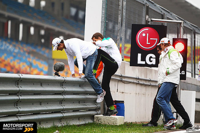 Адриан Сутиль и Нико Хюлькенберг с механиками перелазят защитное ограждение на Гран-при Турции 2011