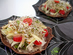 Raw bread topped with tahini, green onions, cabbage, zucchini, tomatoes, and alfalfa sprouts