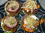 zucchini disks topped with raw burgers, marinated/dehydrated red onions, carrot disks, cabbage, and alfalfa sprouts