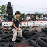 Kai on a pile of tires at the bottom of one of the big slides. Kids ride the tires down the slide.
