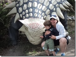 posing with a dino at the zoo
