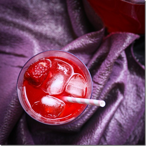 Kompot beverage with ice and floating raspberry