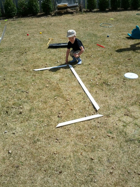 Kid building the letter J out of scrap wood