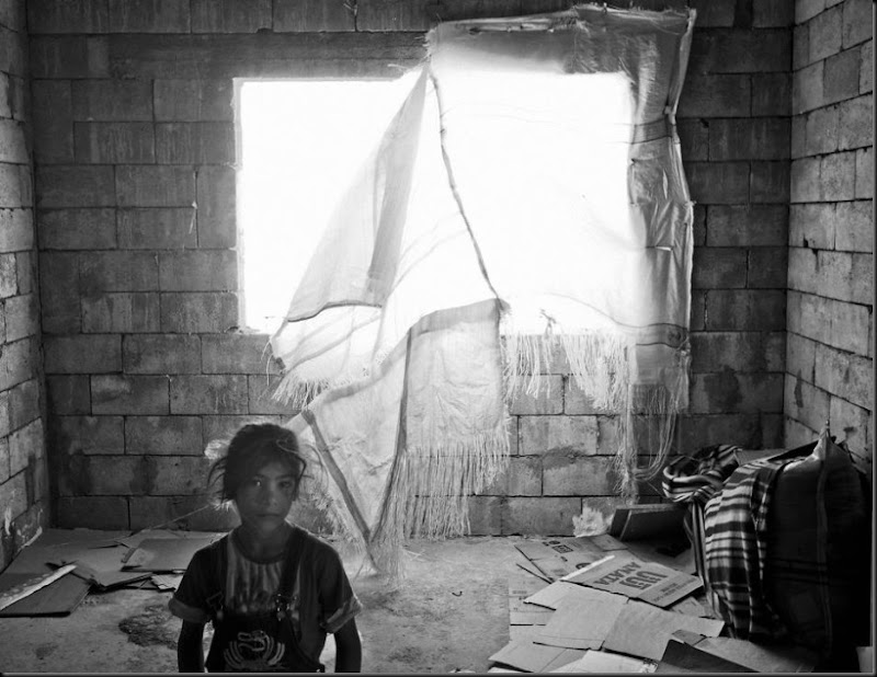 A young Syrian refugee inside her family's temporary home in an unfinished building. (Moises Saman/Magnum Photos for Save the Children)