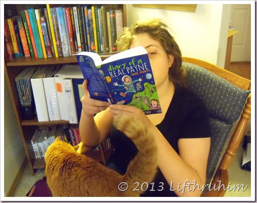 TailorBear reads Diary of a Real Payne with cat on her lap.