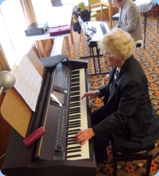 Ngaire McRae playing the Club's Clavinova whilst Len Hancy studies the layout of the Yamaha Tyros