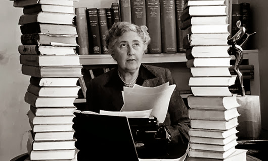 Volume 2, Page 114, Picture, 21. Literature Mystery author and writer, Agatha Christie, pictured at her home, Winter-Brook House, sitting behind her desk with books piled high.