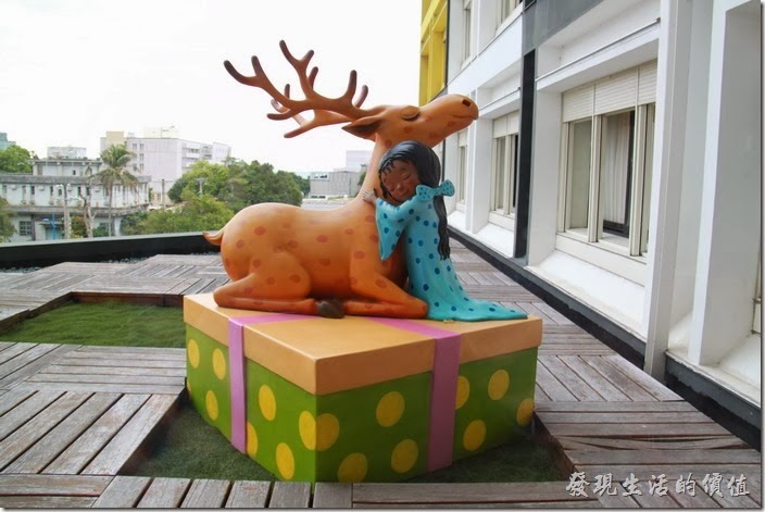 花蓮-翰品酒店。三樓的陽台上有個穿著睡衣的小女孩站在一個禮物盒子上，正抱著一隻靡鹿，似乎在感謝麋鹿送來禮物。