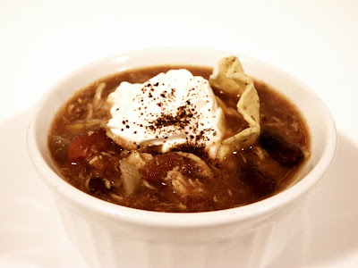 Slow cooker chicken tortilla soup - garnished with sour cream, a tortilla chip, and a sprinkle of chili powder