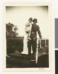 Een Wehrmacht soldaat met een kind op zijn arm op een bruggetje