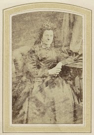 Portret van een oude vrouw in een jurk bij een tafel