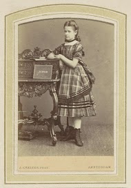 Portret van een meisje in een jurk met Schotse ruit bij een lessenaar met boeken