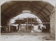 Interieur van een halfronde fabriekshal met een machine en leidingen