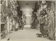 Binnengalerij met kransen en bidstoelen op een begraafplaats