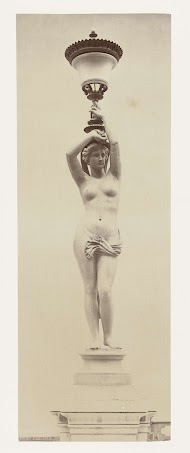 Vloerlantaarn in de vorm van een naakte dame, zij houdt op haar hoofd een kelk vast.