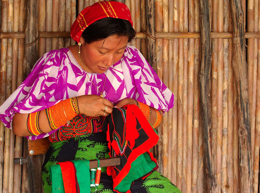 A woman on Isla Naluego works on a mola, a type of needlework.